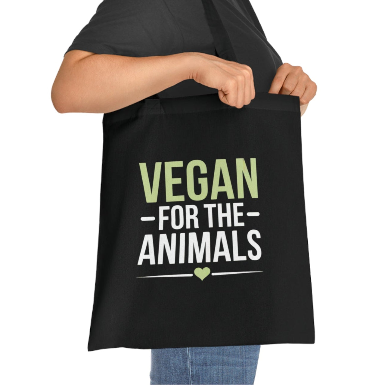 Woman holding a black tote bag with 'Vegan for the Animals' text on a white background