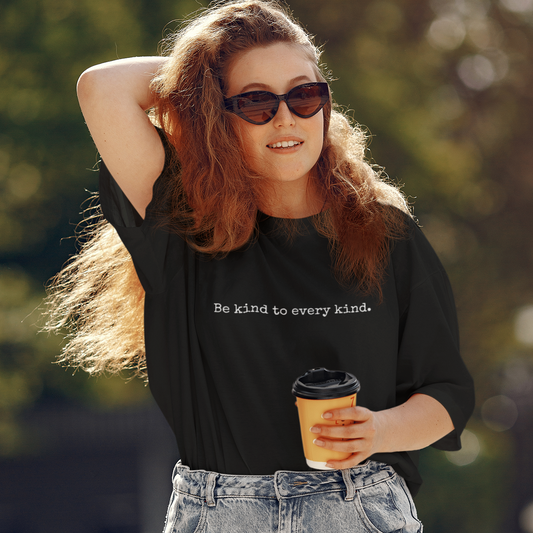 Woman wearing a black minimalist vegan t shirt with 'be kind to every kind' written in a small typewriter font.