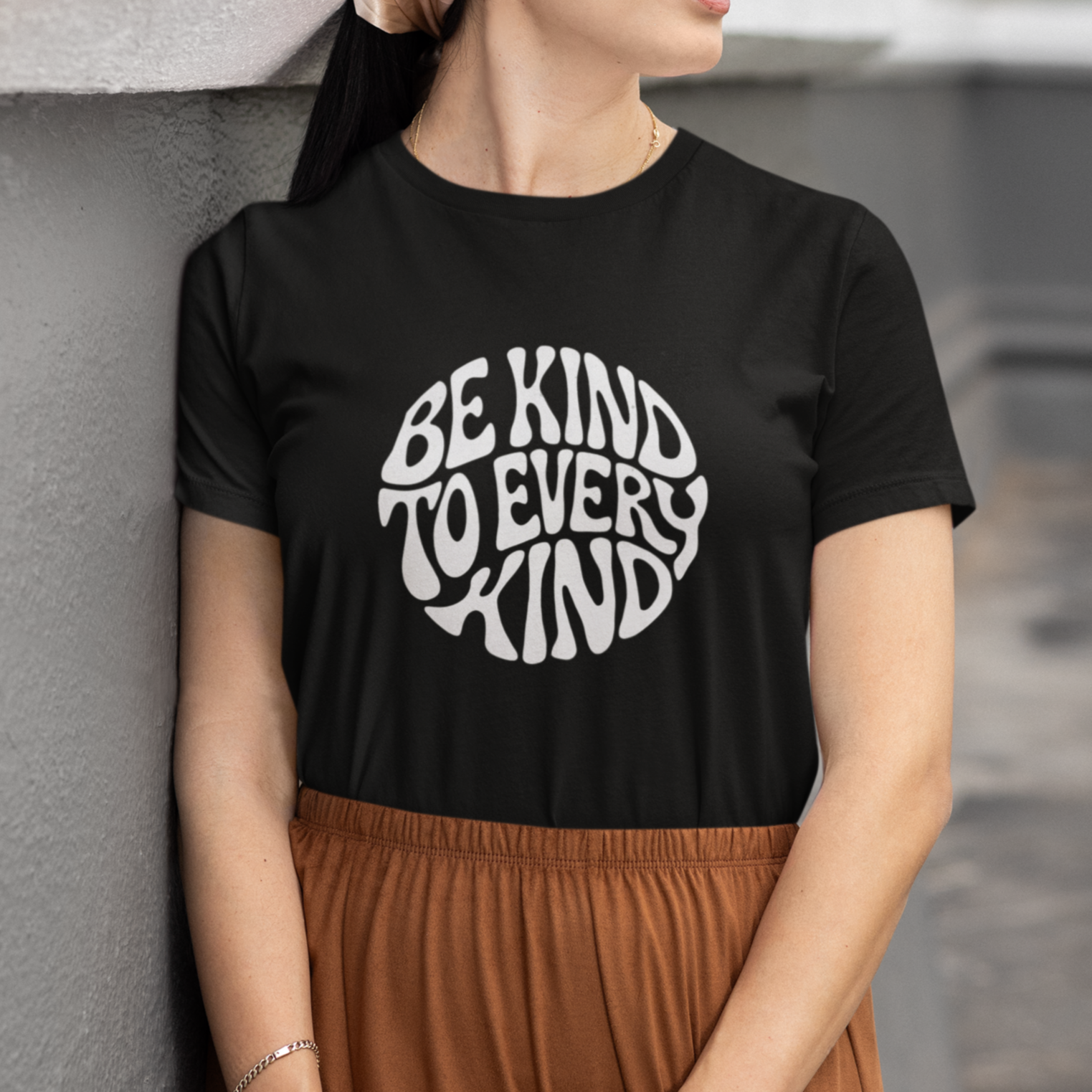 Woman wearing a black vegan t-shirt with a circular slogan 'be kind to every kind'.
