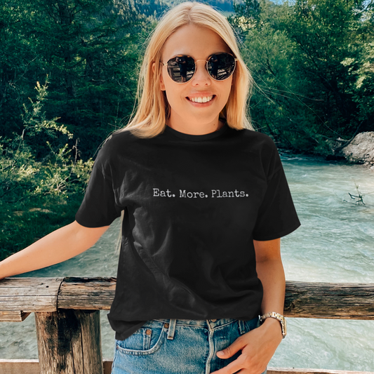 Blonde woman wearing a black minimalist vegan t-shirts saying 'eat more plants'