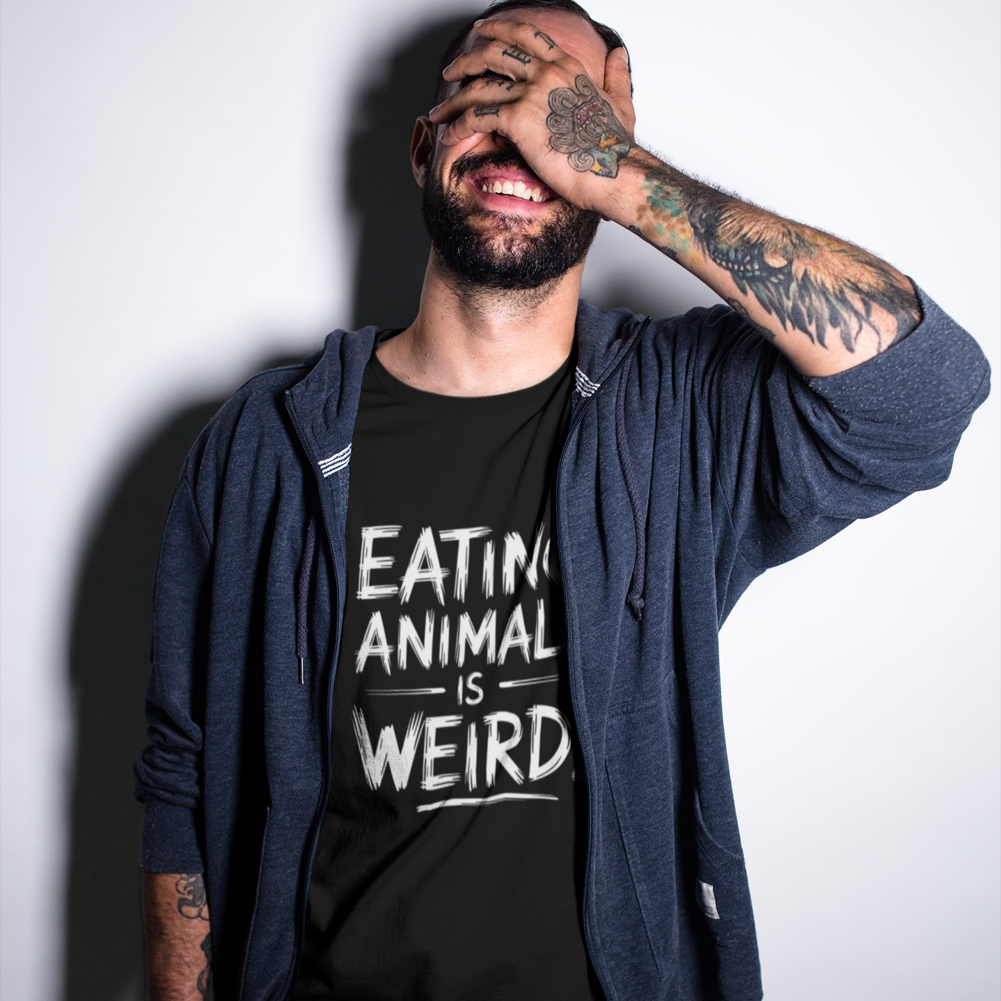 Smiling man wearing a funny vegetarian t-shirt with the slogan 'eating animals is weird'. Perfect for vegans and animal rights advocates.