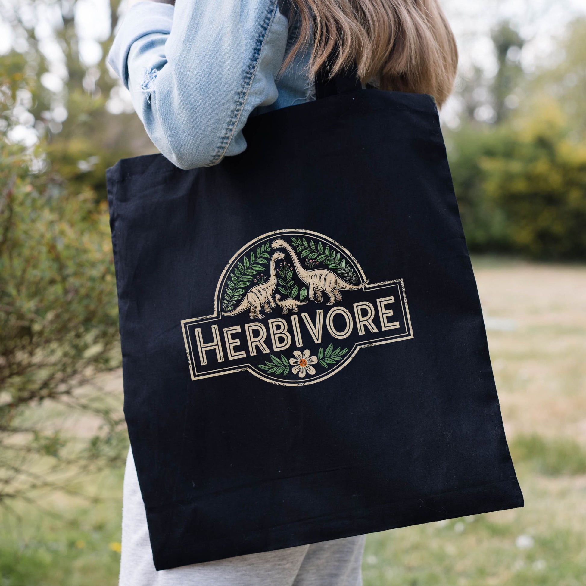 Black vegetarian tote bag with the slogan 'Herbivore' and a dinosaur graphic.