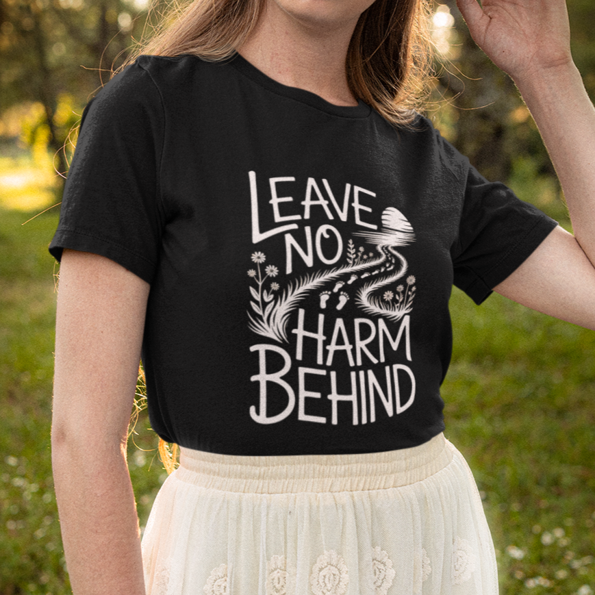 Woman in nature wearing a black vegan t shirt with the slogan 'leave no harm behind'.