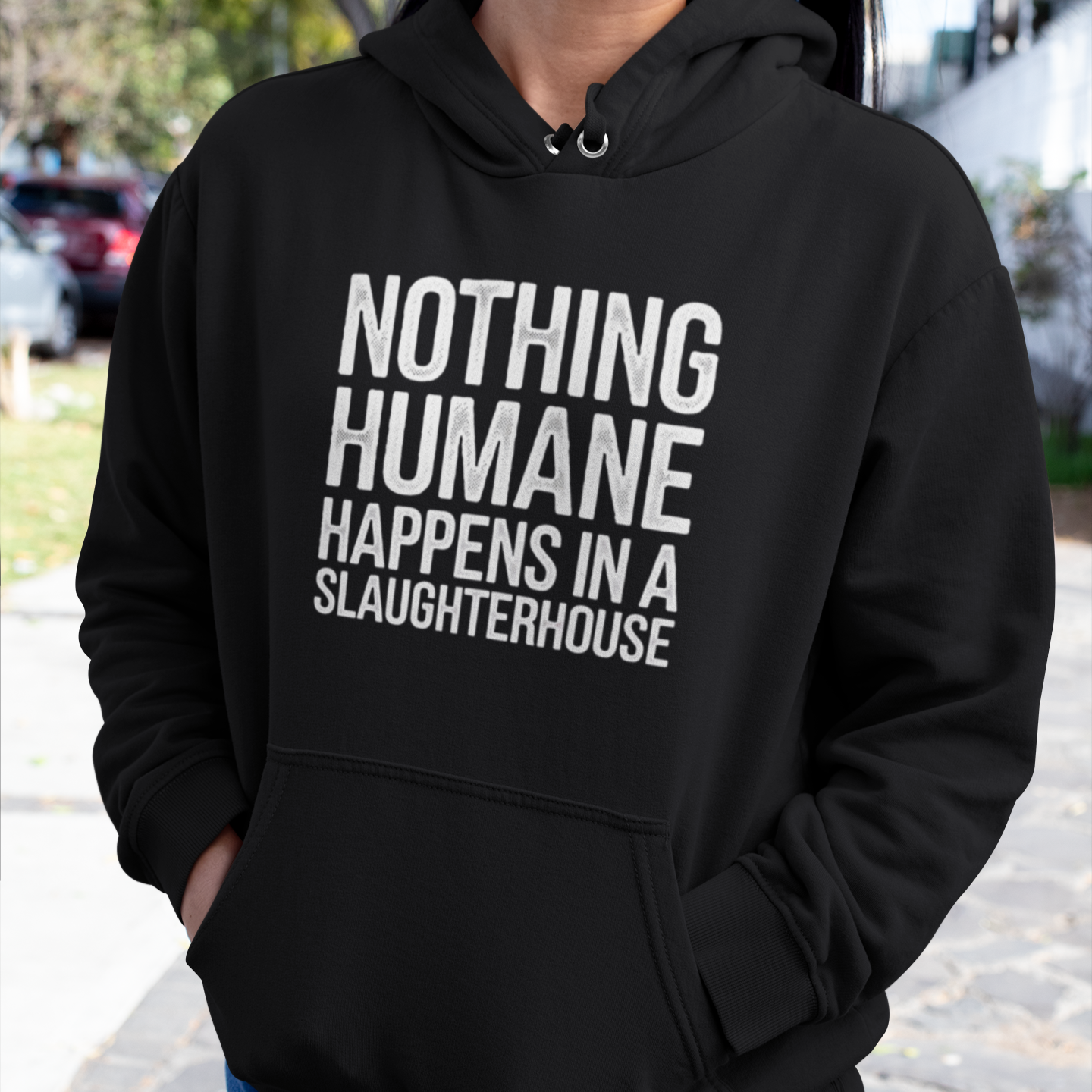 Woman wearing a black animal rights hoodie with the slogan 'nothing humane happens in a slaughterhouse'.
