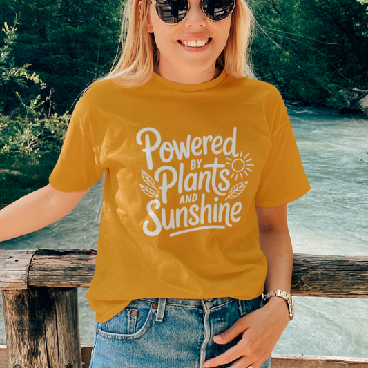 Woman wearing a mustard coloured vegan t-shirt with the slogan 'powered by plants and sunshine'