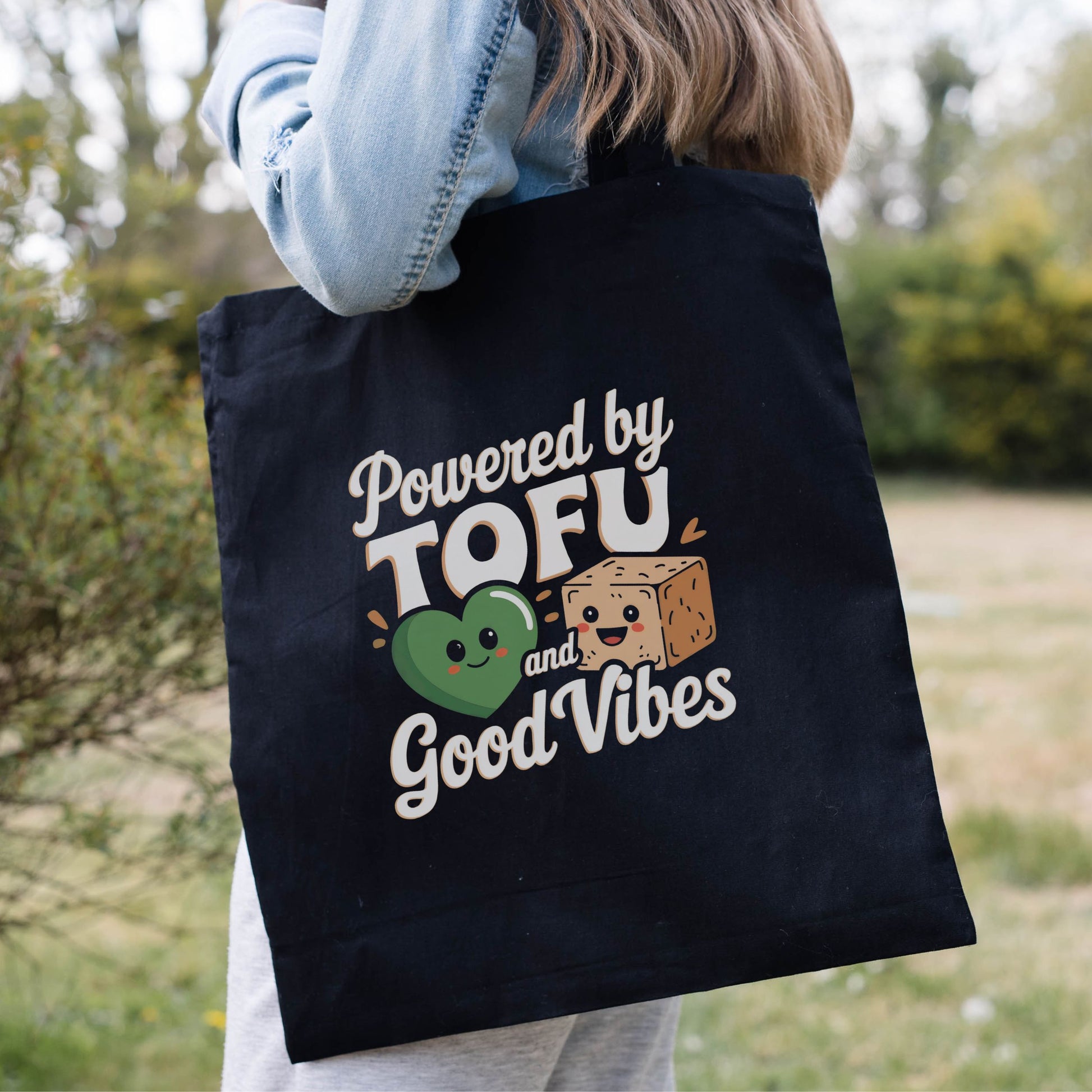 Funny vegan tote bag with the slogan 'powered by tofu and good vibes' and a graphic of a tofu cube and a green heart.