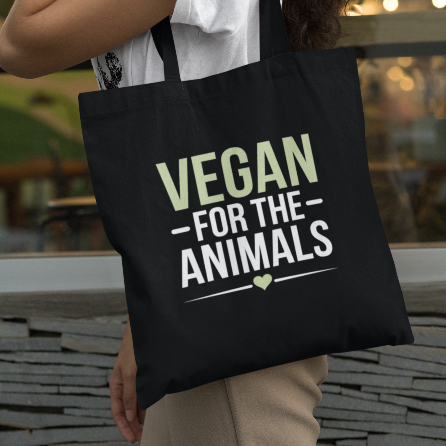 Person holding a black tote bag with 'Vegan for the Animals' text.