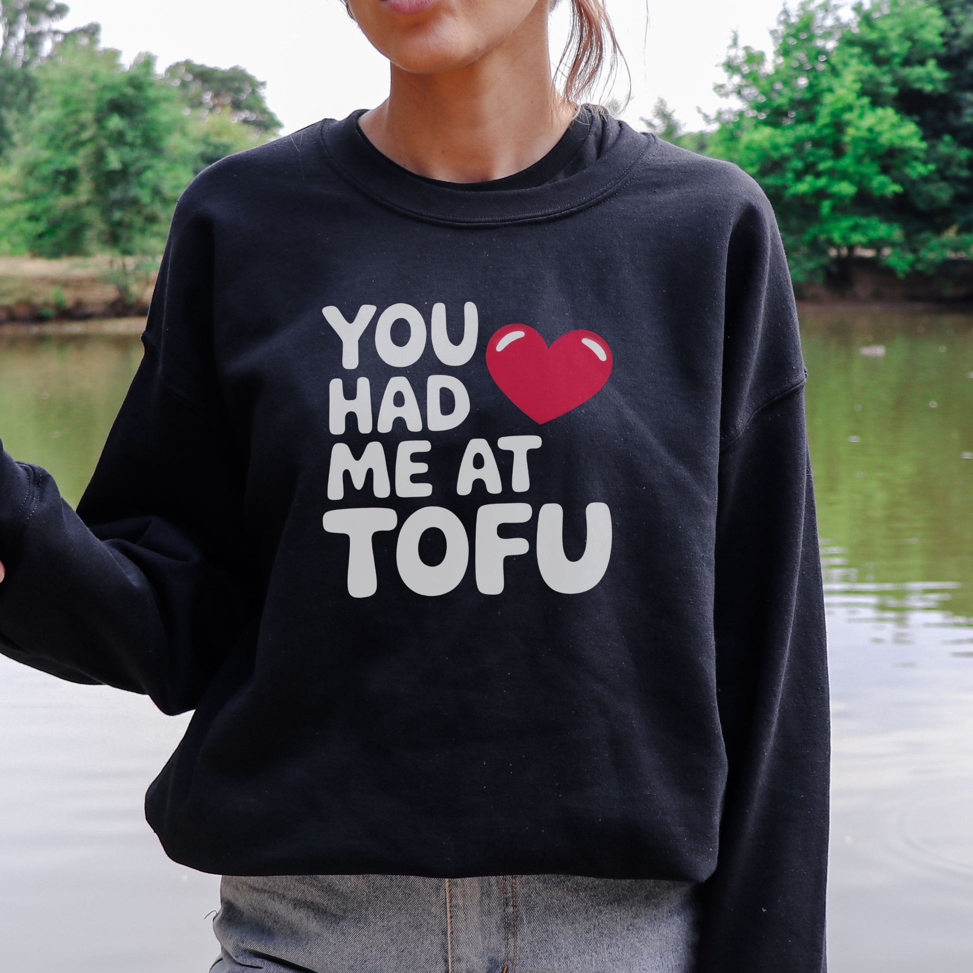 Woman wearing a black vegan sweatshirt with the slogan 'you had me at tofu' and a red heart.